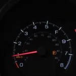 Car dashboard showing check engine light and low fuel indicator